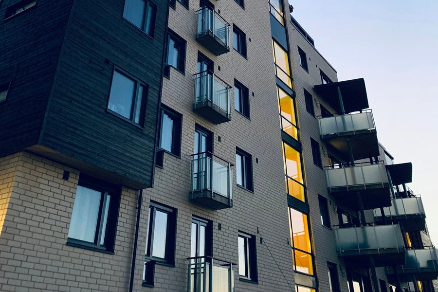Prédio de apartamentos ao entardecer, com uma janela iluminada