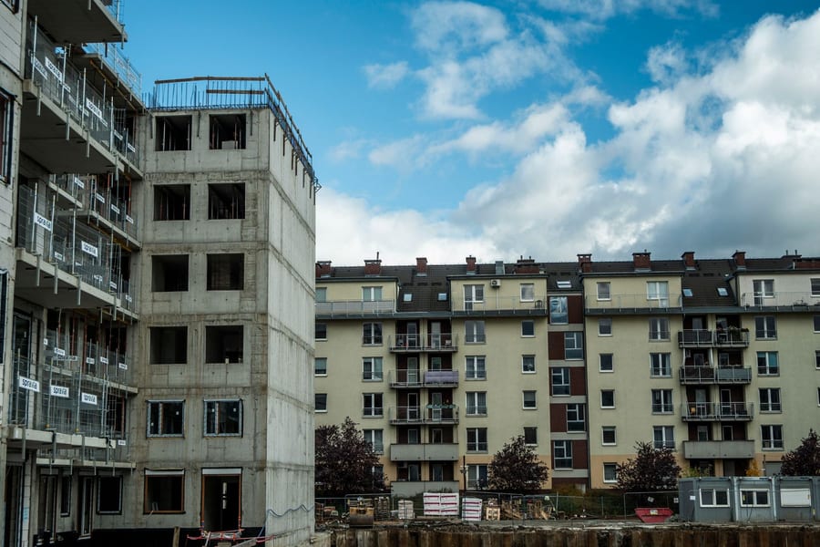 Prédio de habitação em construção ao lado de edifícios residenciais, sob céu azul